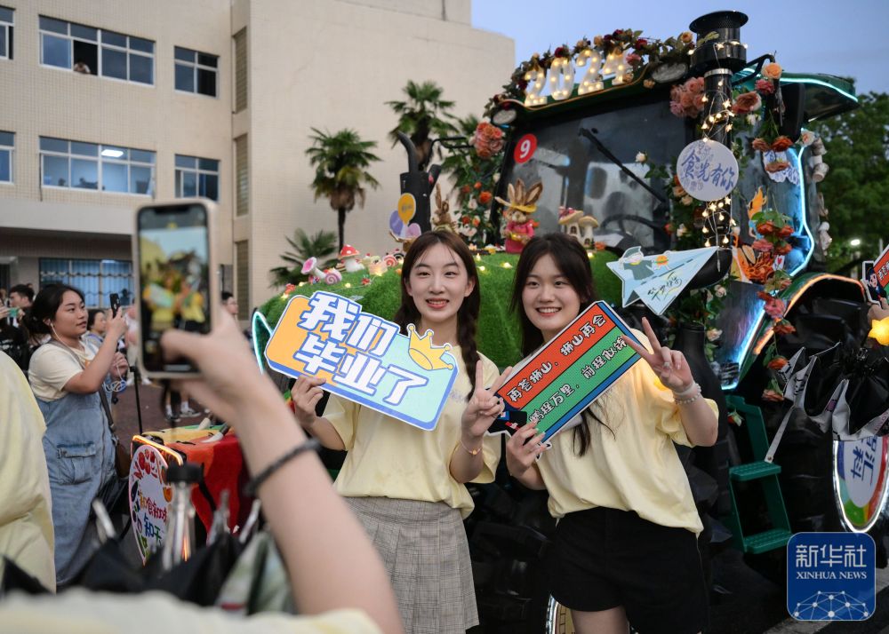 6月21日,华中农业大学学生在农机花车前拍照留念。
