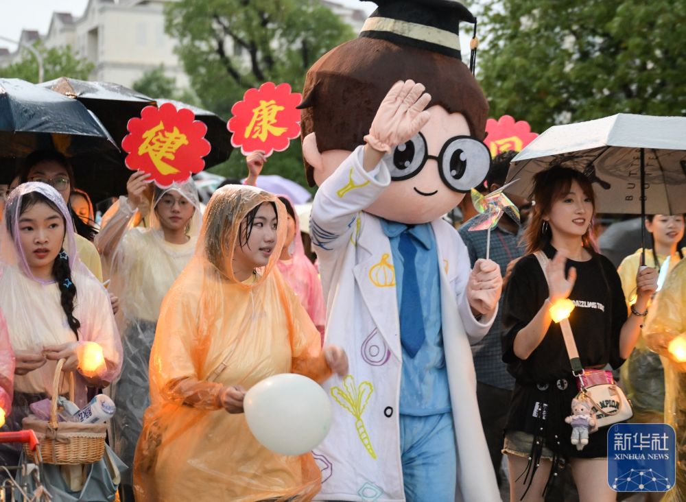 6月21日,华中农业大学学生在校园里冒雨巡游。2